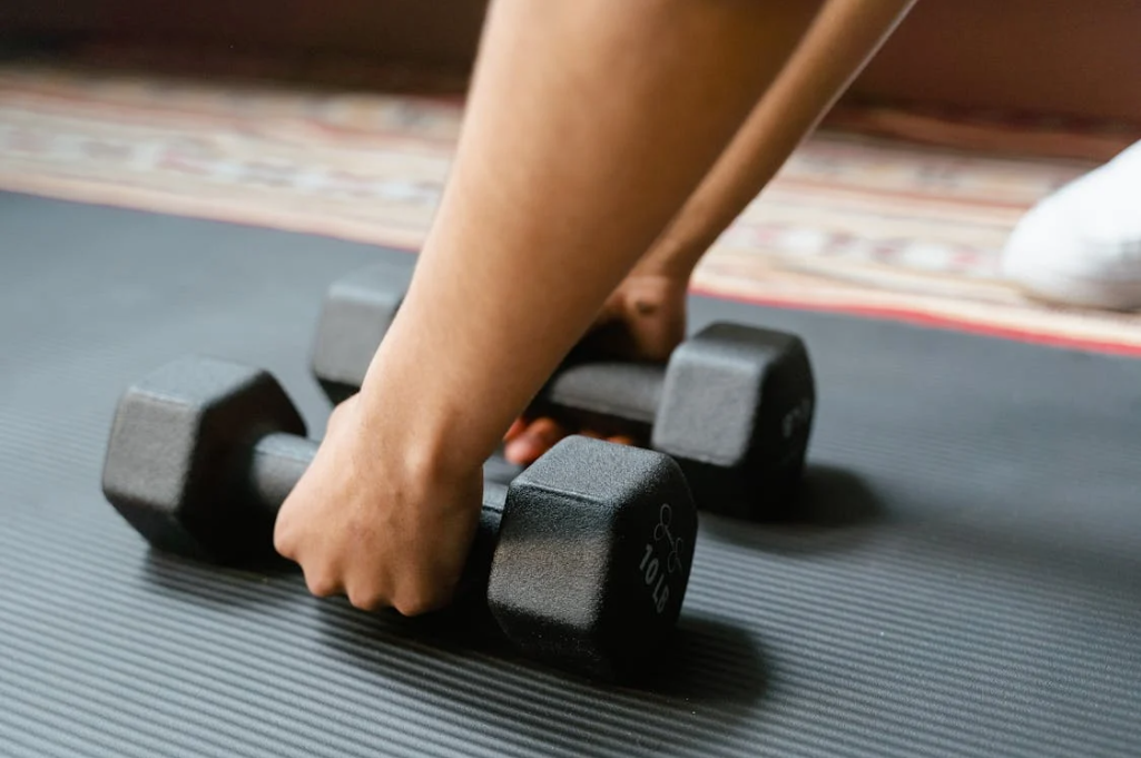 Women applying muscle gaining strategies in the gym doing dumbbell exercises