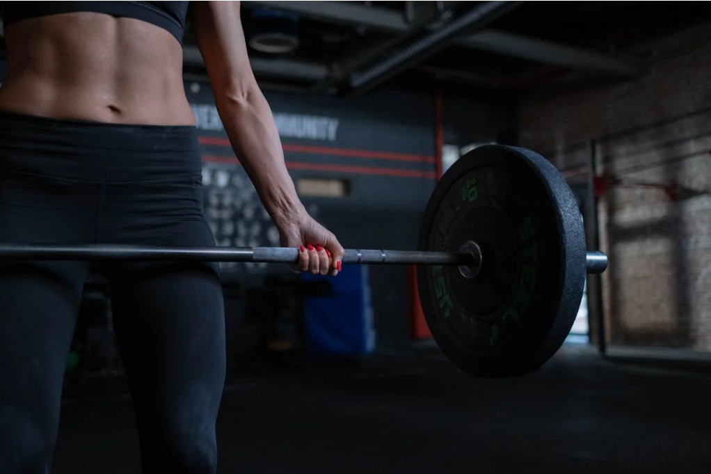 A toned, muscular woman lifting a heavy barbell.