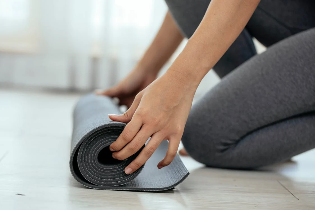 Women unrolling yoga matt after maintaining workout motivation