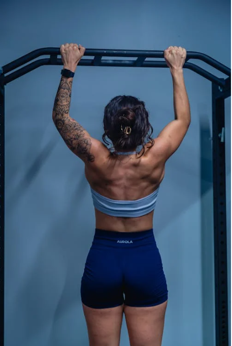Woman doing a dead hang in the gym.