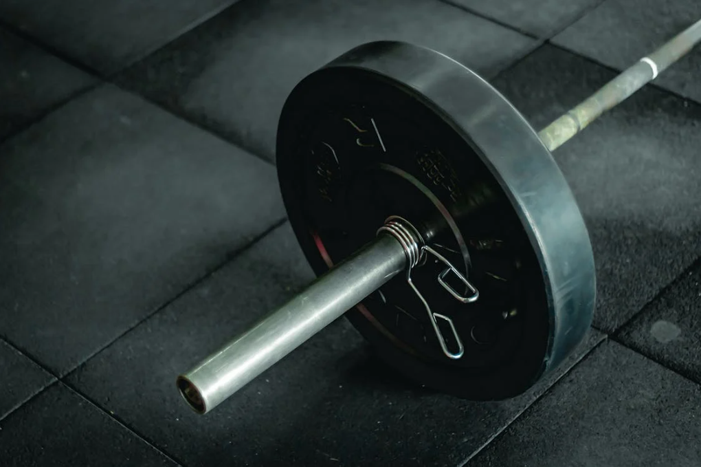 Barbell with 45 pound plate laying on the gym floor